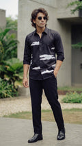 Man wearing a dark patterned shirt and sunglasses outdoors